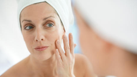 Woman with towel on her head applying Bepanthen Derma face cream