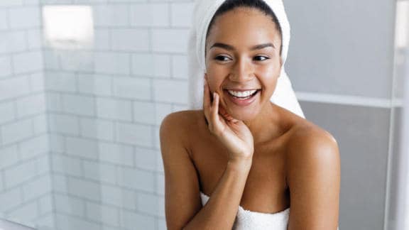 Mladá žena s ručníkem na hlavě šťastná po použití produktů Bepanthen DERMA