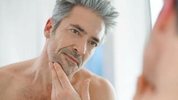 Spokojený muž si sahá na tvář po použití produktu Bepanthen DERMA