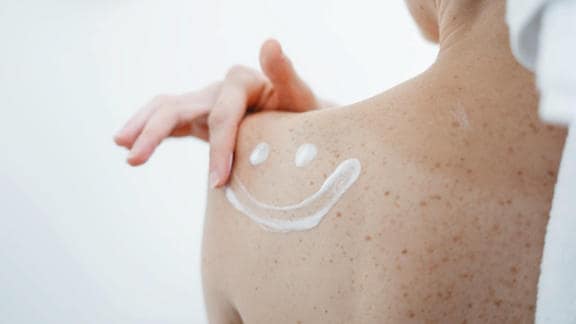 Usměvavý emotikon nakreslený tělovým mlékem Bepanthen DERMA na pokožku
